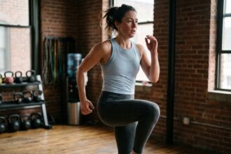 Femme effectuant un exercice HIIT de montées de genoux dans une salle de sport urbaine compacte